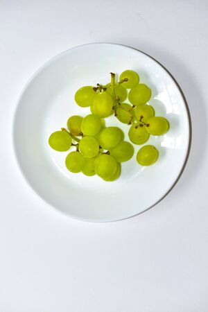 Green delicious ripe grapes on a white plateの写真素材
