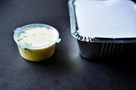 Aluminum container with food and white sauce with a jarの写真素材
