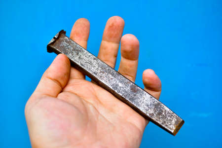 Steel chisel in the hands of a master on a blue backgroundの写真素材