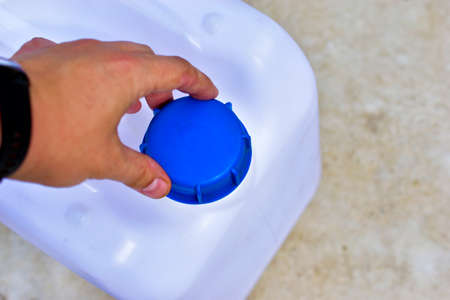 A white plastic canister with a blue lid in the hands of a manの写真素材