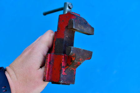 Small iron vise in hand on a blue backgroundの写真素材