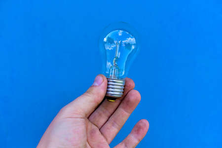 Glittering incandescent lamps in hand on a blue backgroundの写真素材