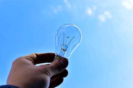 Glittering incandescent lamps in hand on a blue backgroundの写真素材