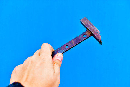 Small metal hammer in hand on a blue background