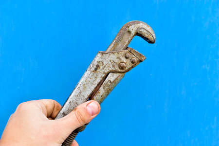 Iron gas wrench in hand on a blue background