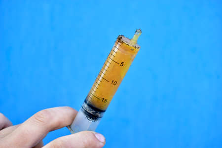 Lubricants in a syringe in your hand on a blue backgroundの写真素材