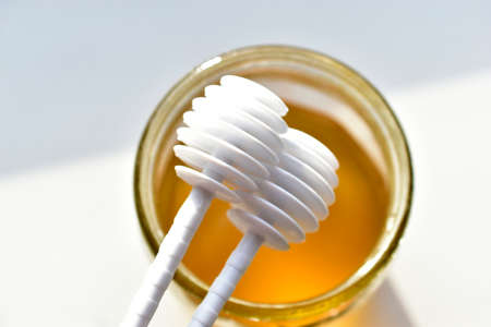 Two white plastic spoons for the honeyの写真素材