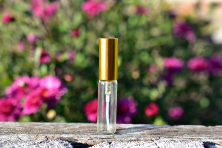 Small empty perfume sample bottle on a background of flowers
