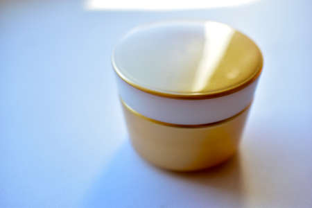 Yellow and white jar with white cosmetic creamの写真素材