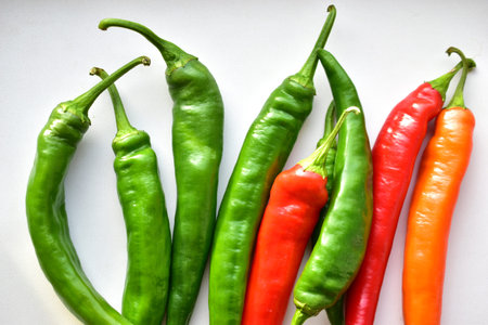 Green and red capsicum fruits on a white background