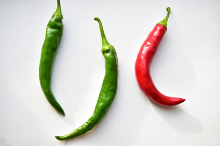 Green and red capsicum fruits on a white background