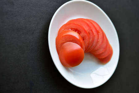 Sliced red ripe tomatoes on a white plateの写真素材