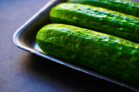 Green ripe cucumbers in a package on a black backgroundの写真素材