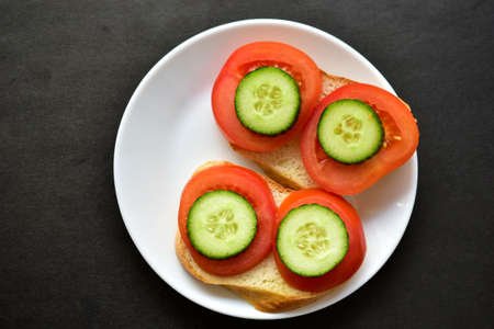Sandwiches on a white plate with cucumber and tomato on white breadの写真素材