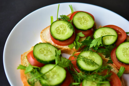 Diet sandwiches with greens, cucumber and tomato on a white plateの写真素材