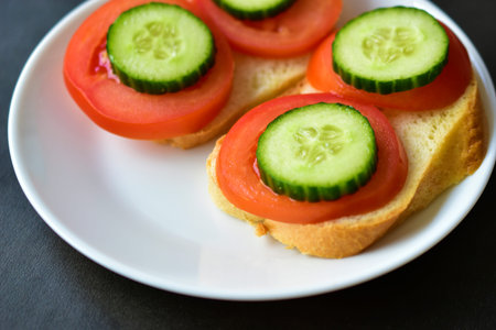 Sandwiches on a white plate with cucumber and tomato on white bread