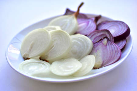 Blue and yellow onion cut into round pieces on a white plateの写真素材