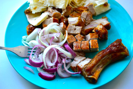 Slices of roast pork with pickled onions on a plateの写真素材