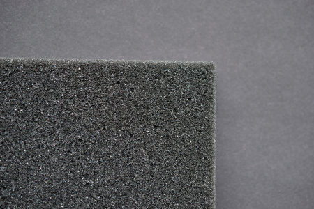 A piece of foam rubber and polystyrene in holes on a black background