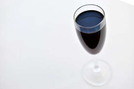 Small glass of red wine on a white background with shadowsの写真素材