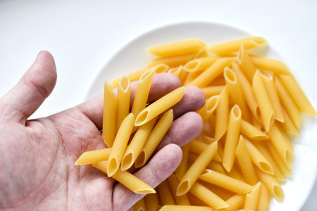Yellow delicious pasta close-up in a man's hand