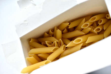 Yellow macaroni from a paper box on a white backgroundの写真素材