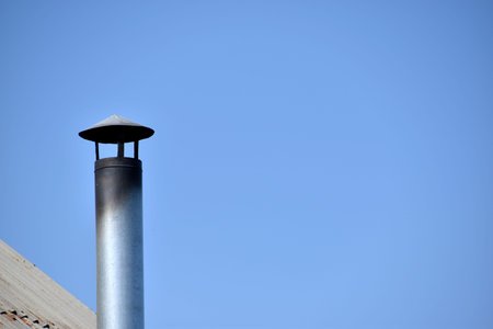 Silver stove pipe in the house against the blue sky