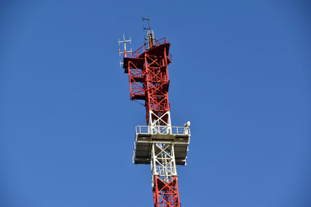 Red and White High rise communication tower Antenna in the city with transmitters