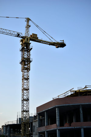Yellow tower crane its boom is a building under construction