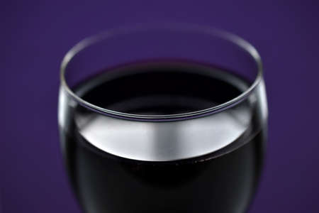 A large glass of red wine on a purple backgroundの写真素材