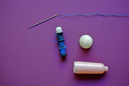 Blue spools of thread on a purple background with needles