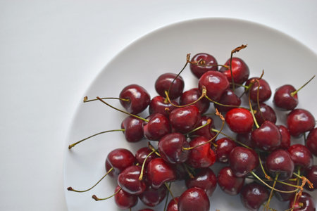 Red and ripe cherries on a white plate