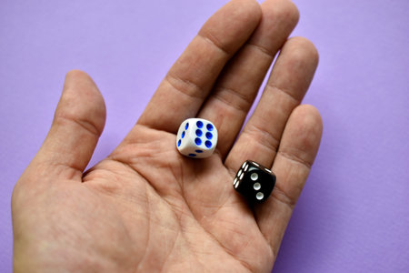 The dice are black and white in the player's hand on a purple background
