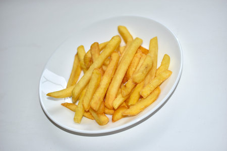 Fried French fries on a white plate close-up