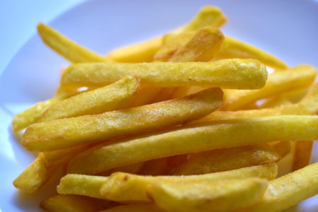 Fried French fries on a white plate close-up
