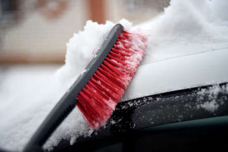 Red car brush for cleaning snow in winter in the snowの写真素材