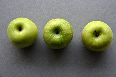 Three delicious green apples on a gray backgroundの写真素材