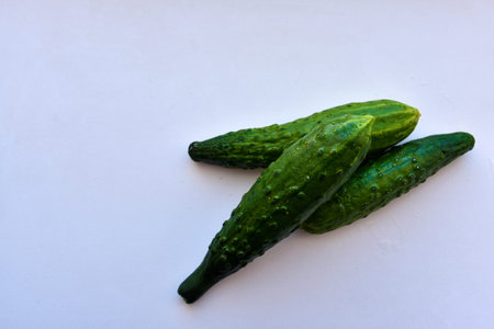 Three green fresh cucumbers on a white background
