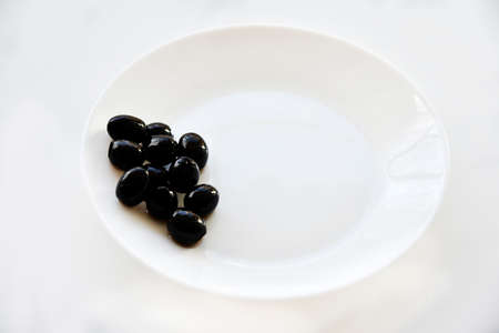Pickled black olives on a white plate with a forkの写真素材