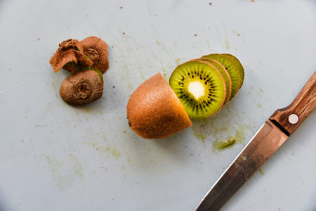Slicing kiwi fruit with a knife on a boardの写真素材