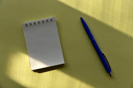 Blue fountain pen and notepad on a yellow backgroundの写真素材