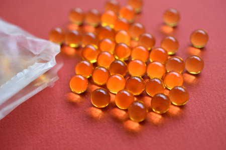 Yellow fish oil balls in a bag on a red backgroundの写真素材