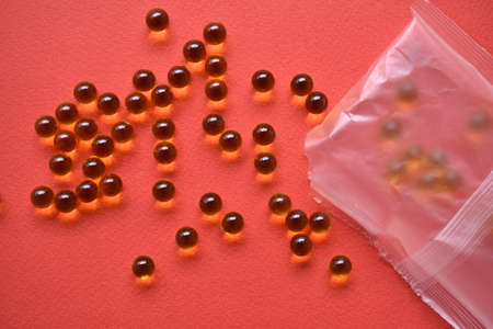 Yellow fish oil balls in a bag on a red backgroundの写真素材