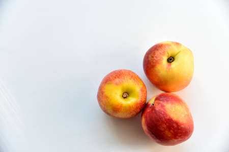Yellow-red juicy peach nectarine on a white plateの写真素材