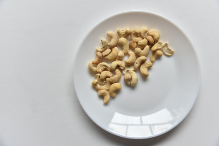 Cashew nuts on a white plate in a group of loose. Cashew nuts white plate on white background. nature background. healthy eating.の写真素材