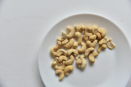 Cashew nuts on a white plate in a group of loose. Cashew nuts white plate on white background. nature background. healthy eating.の写真素材