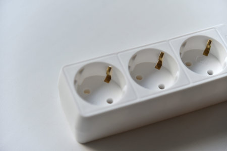 White electrical extension cord mains filter with sockets on a white background. Flat icon on white...