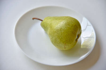 Green delicious pears on a white plate close-up.Vegetarian food.の写真素材