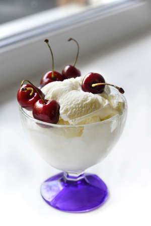 Creamy sweet ice cream in a glass ice cream maker with large cherry berries. isolated object.の写真素材