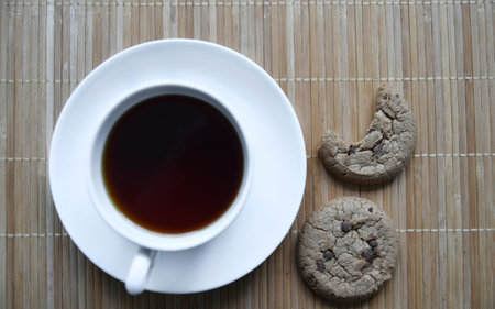 Tea pair and oatmeal cookies with chocolate on a mat. Delicious breakfast with tea and sweet...